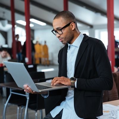 Young African American man in the office looking at his laptop.