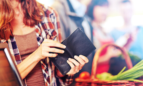 Closeup of woman looking for cash in her wallet.