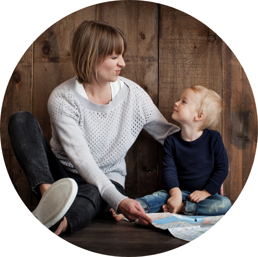 A mother and child sit side by side making silly faces at each other.