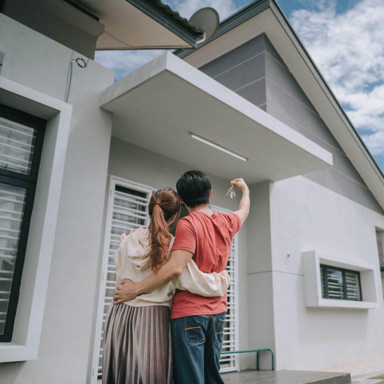 Happy couple standing outside of the new home they purchased with an adjustable rate mortgage.