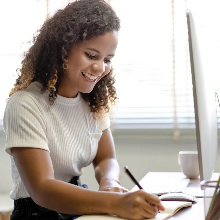 Woman seated at desk smiling, going over her finances.