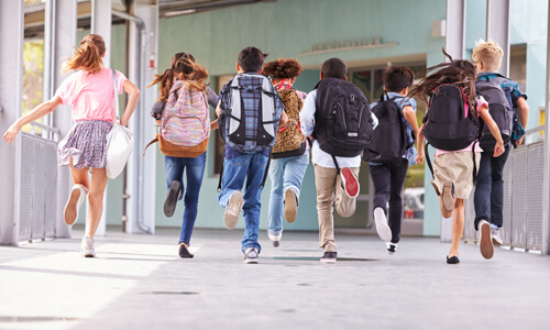 Group of children running towards school.