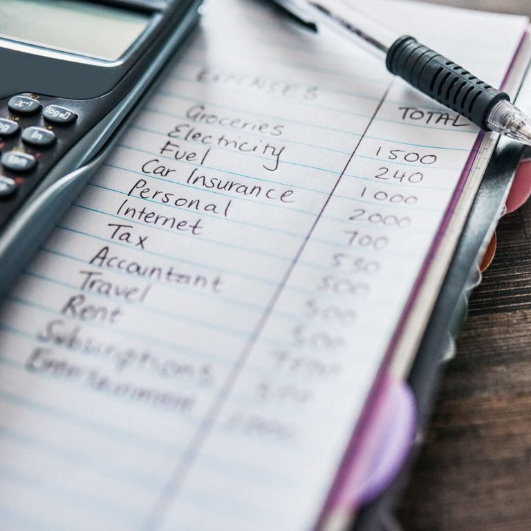 Budget line items written in notebook next to a calculator.