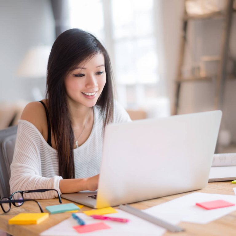 College student sitting at laptop and reviewing her budget.