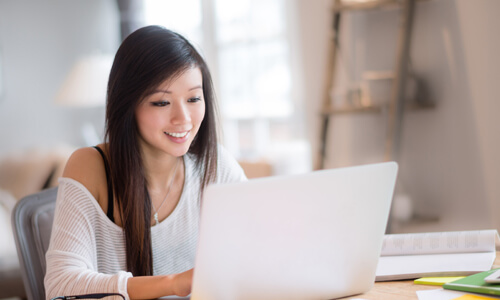 College student sitting at laptop and reviewing her budget.