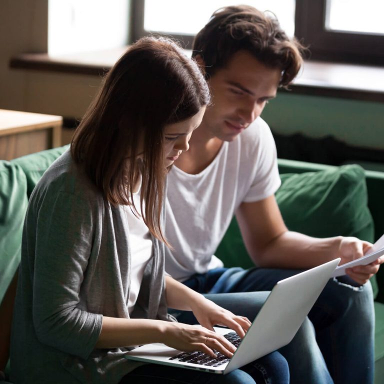 Couple seated on couch reviewing their finances.