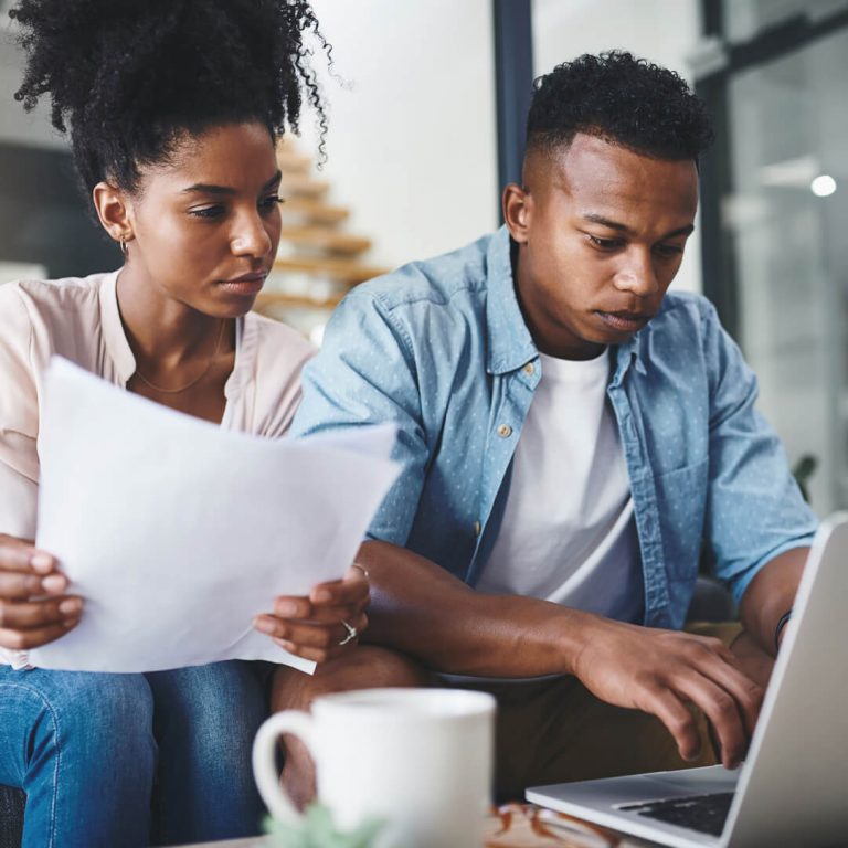 Couple seated on couch with laptop reviewing their credit report, disputing an error.