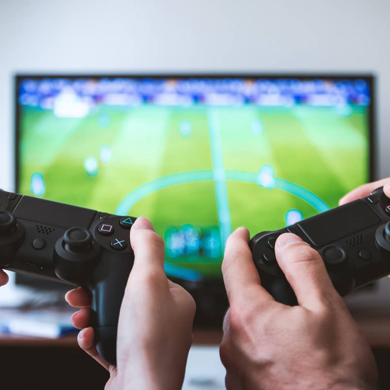 Closeup of two pairs of hands holding joysticks, playing video game.