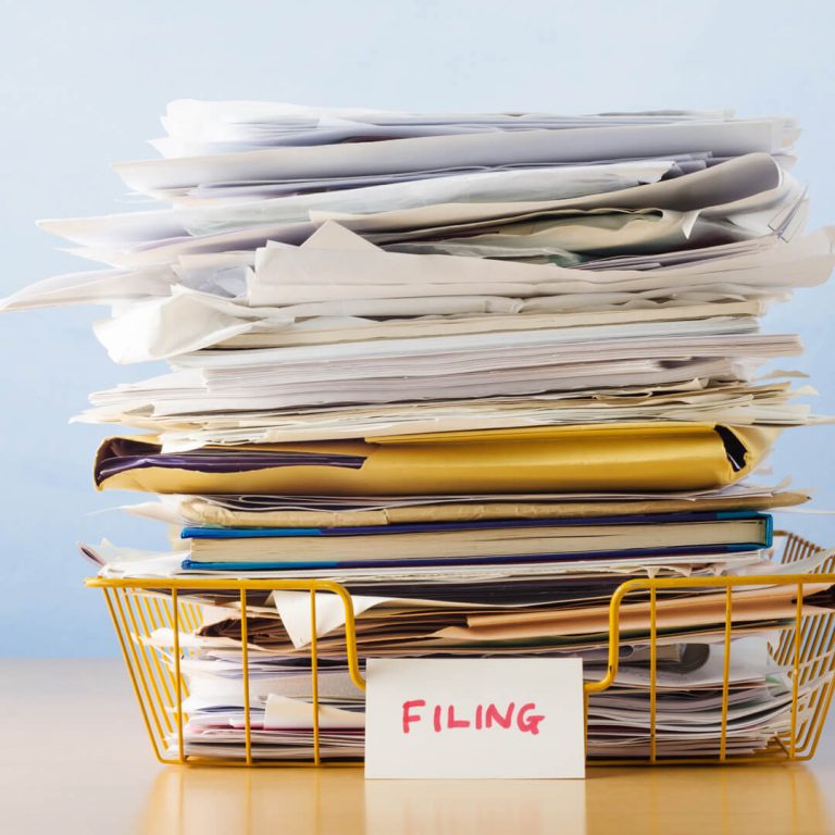 Stack of papers in filing bin on desk.