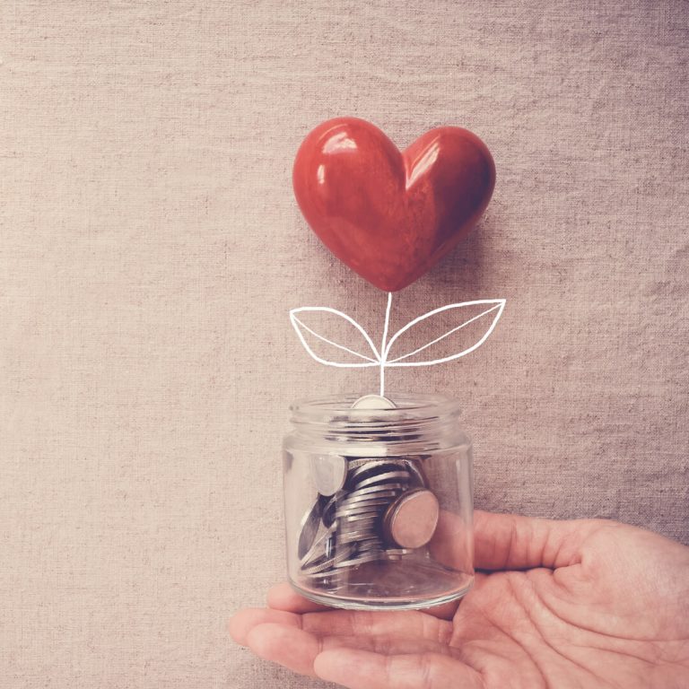 Hand holding jar of coins with heart coming out of jar.