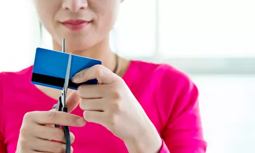Woman cutting up a credit card, going credit card free.