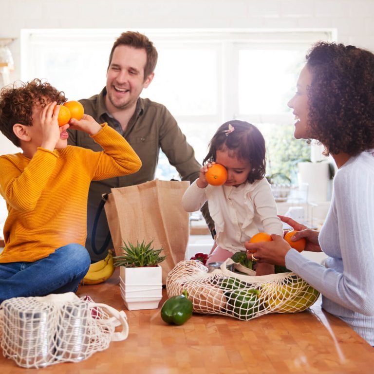 Happy family in kitchen unloading groceries.