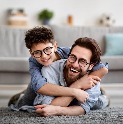 A young dad and his curly haired son show off their new glasses.