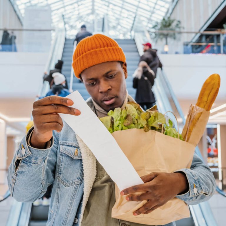 Man reviews his grocery receipts, which are higher due to inflation.