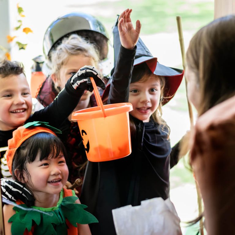 Young kids in Halloween costumes, trick or treating at someone's door.