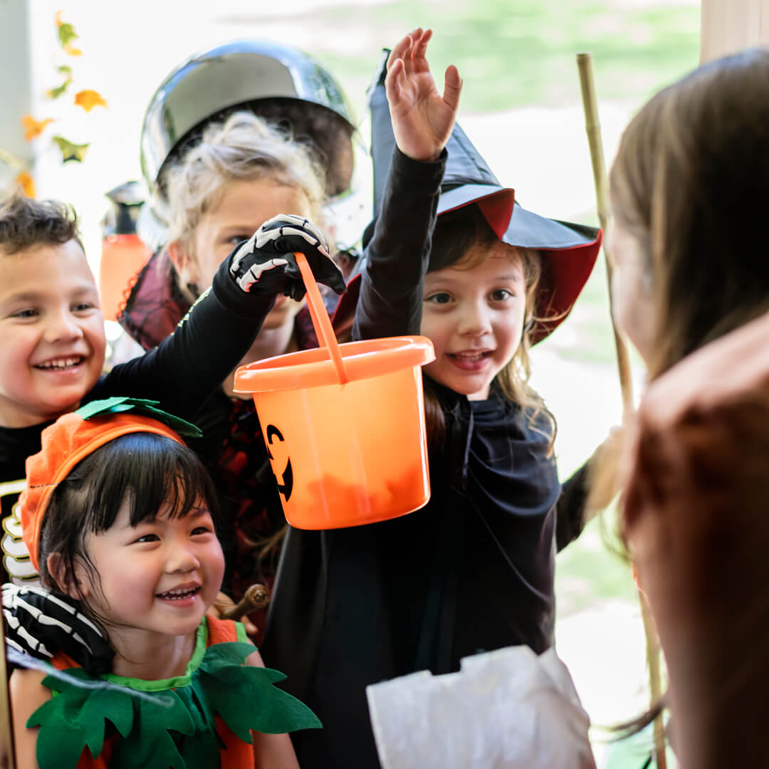 Young kids in Halloween costumes, trick or treating at someone's door.