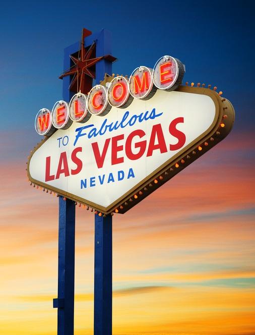 The official Las Vegas sign glows in the desert sunset.