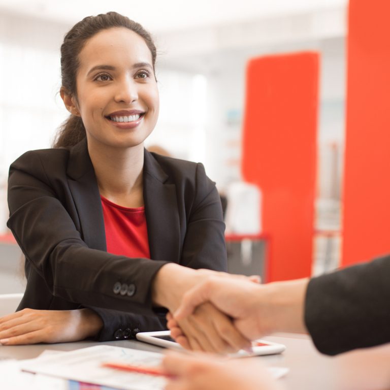 Woman on job interview shaking the hand of the job interviewer.