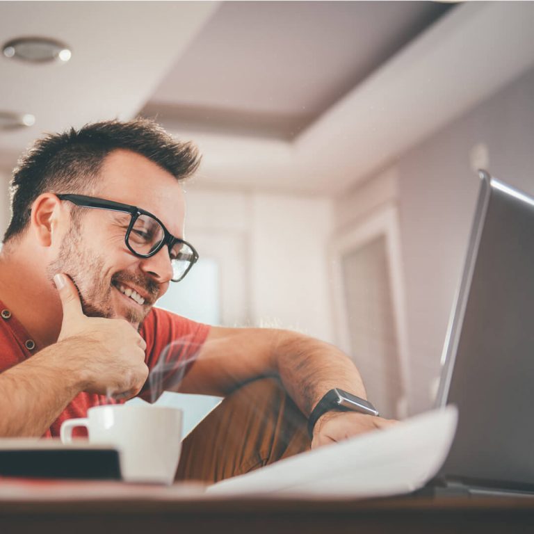 Man reviewing his financial statements on his computer, smiling.