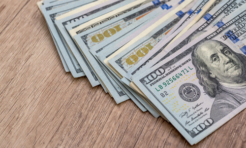Hundred dollar bills on wooden table.