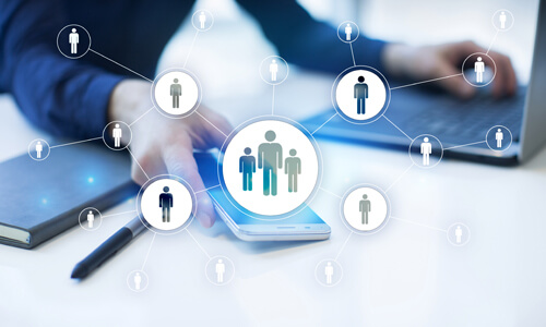 Graphic of people digitally connected, laptop and phone in background.