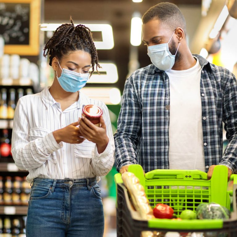 Man and woman shopping at grocery store, budgeting.
