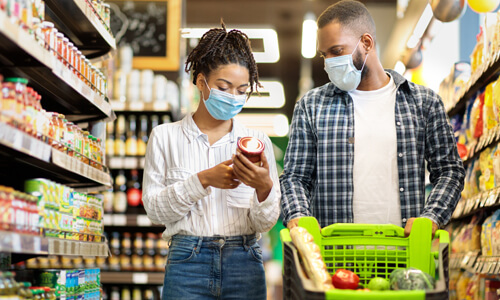 Man and woman shopping at grocery store, budgeting.