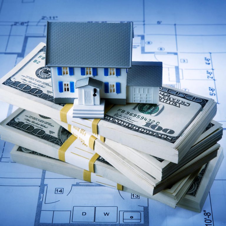 Model home sitting on top of a stack of money.