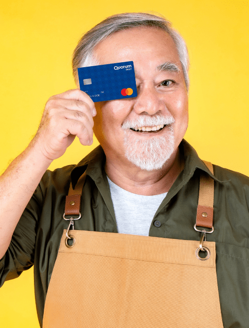 An older man holds up a Quorum Debit Card.