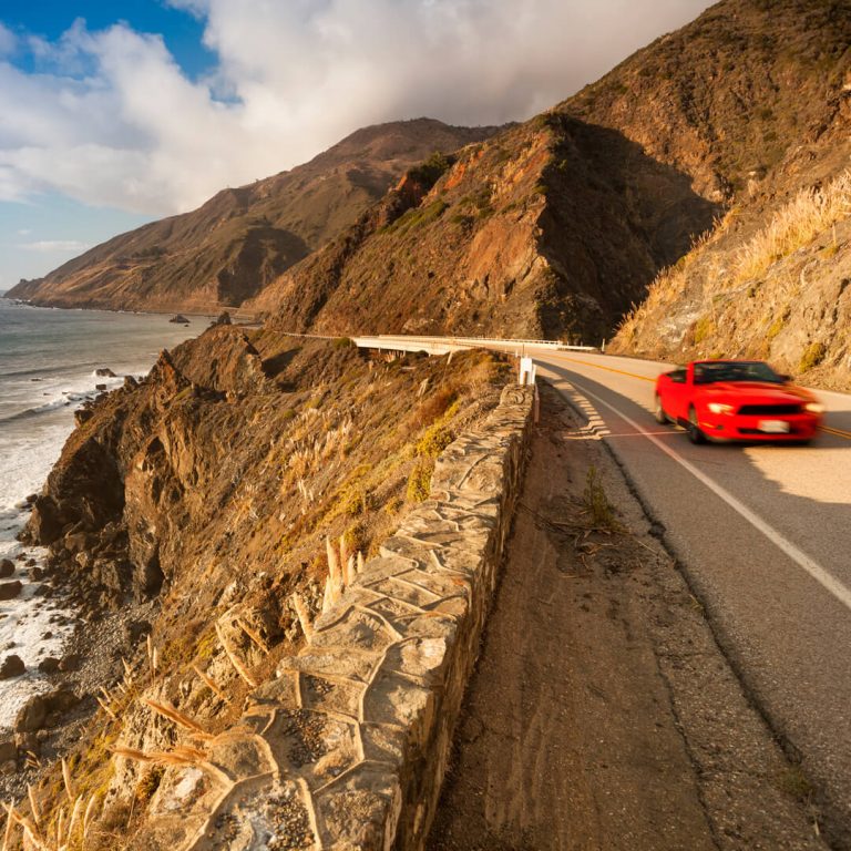 Classic Car driving down Highway 1 in California, a scenic roadtrip.