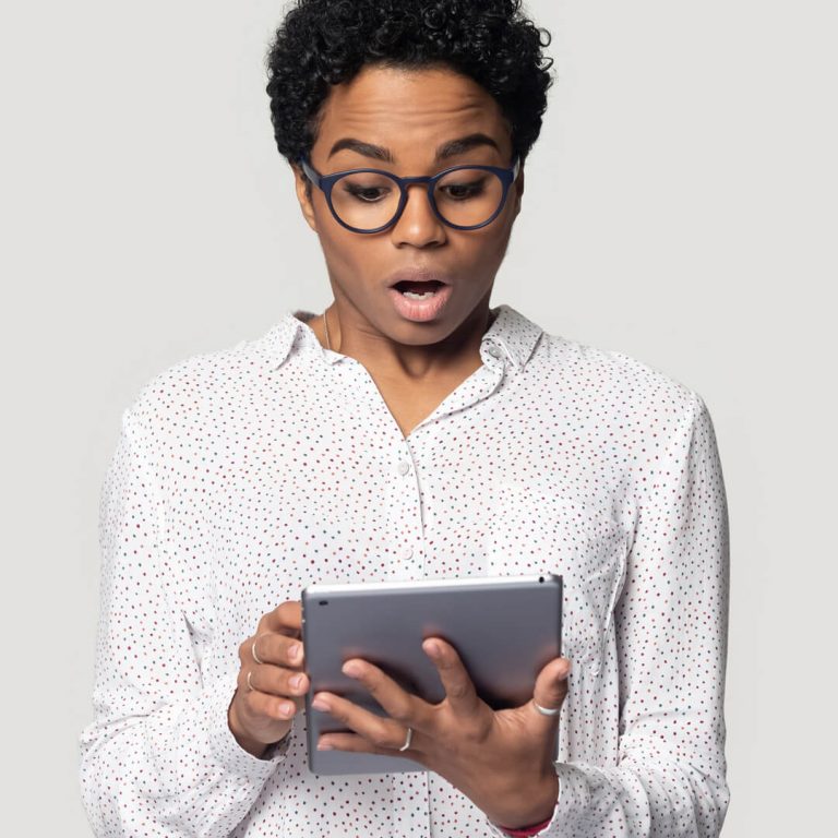 Woman looking at her computer in surprise, the victim of a scam.