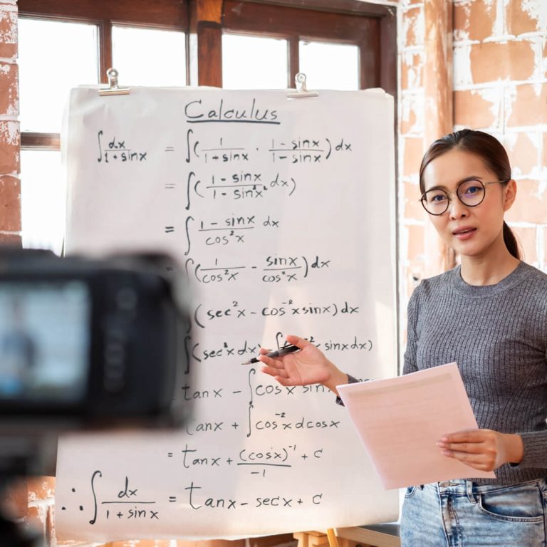 Woman standing in front of classroom, tutoring math, as a side-gig.