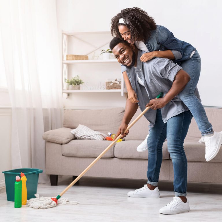 Couple in living room mopping floor, spring cleaning.