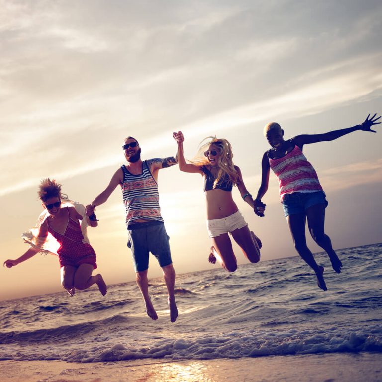 Group of young friends, jumping up on beach, on spring break.