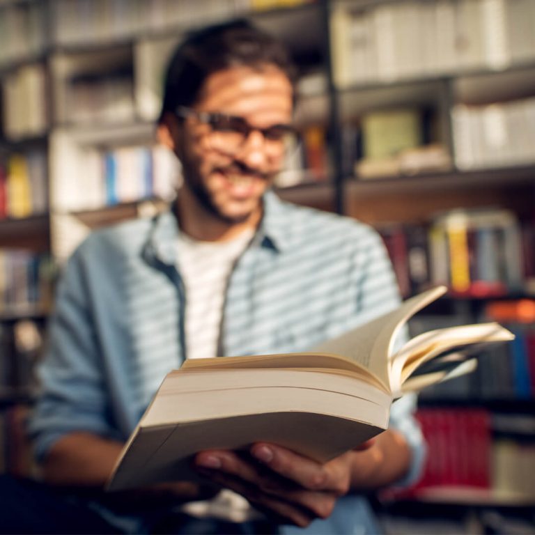 Graduate student in library, reading a book.