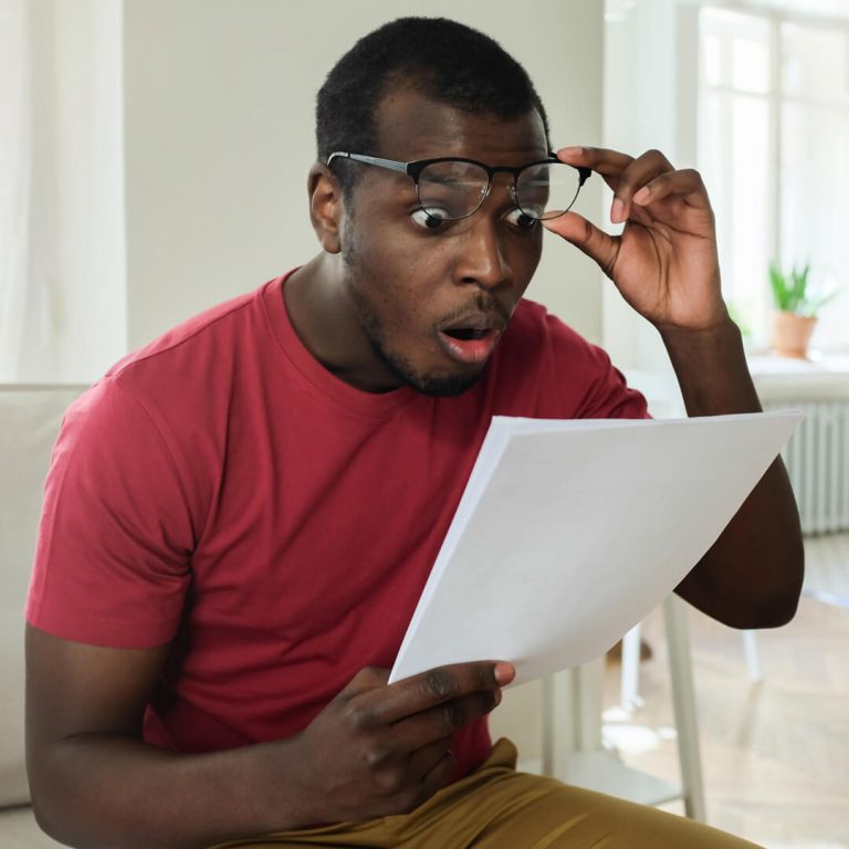 Man looking wide-eyed at his tax bill, in shock.
