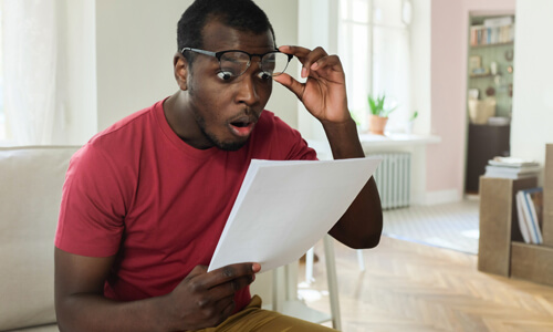 Man looking wide-eyed at his tax bill, in shock.