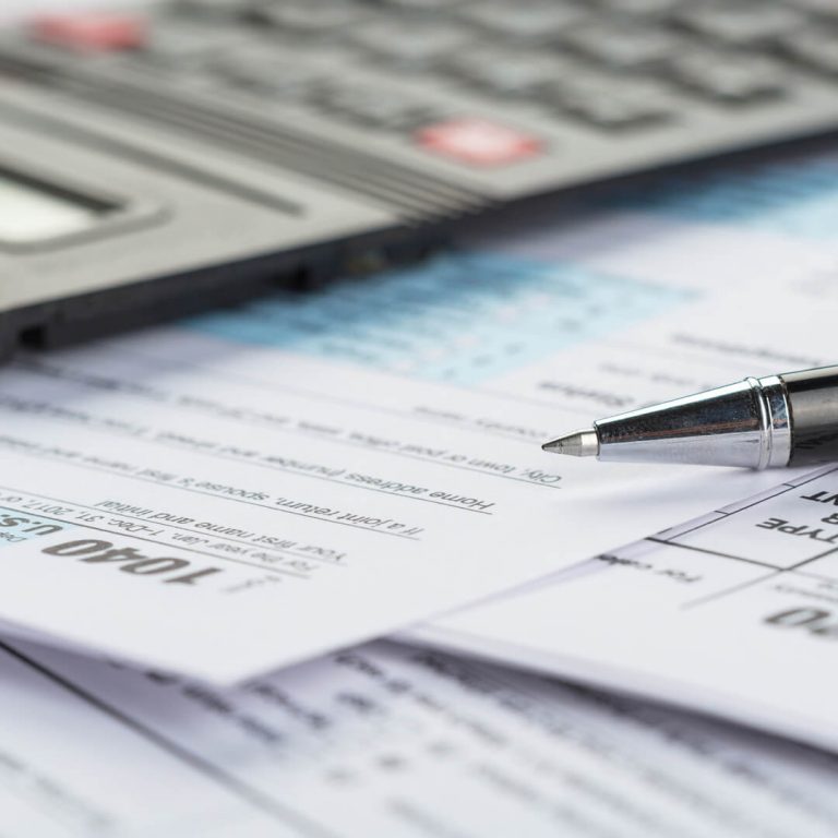 Pen sitting atop tax forms.