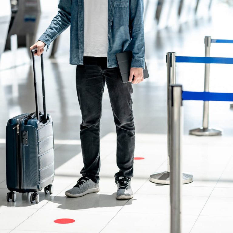 Man with travel insurance waits with suitcase for his flight.