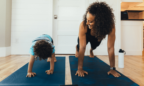 A woman and child doing yoga on a yoga mat in a house.