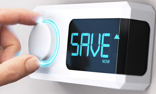 Closeup of hand on thermostat, with the letters SAVE displayed.