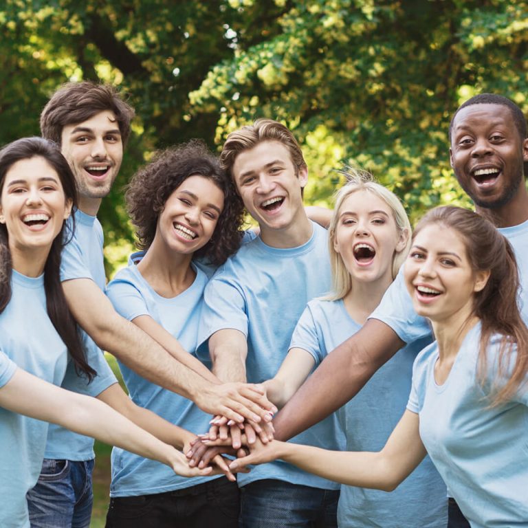 Group of young volunteers standing outside and smiling at camera.
