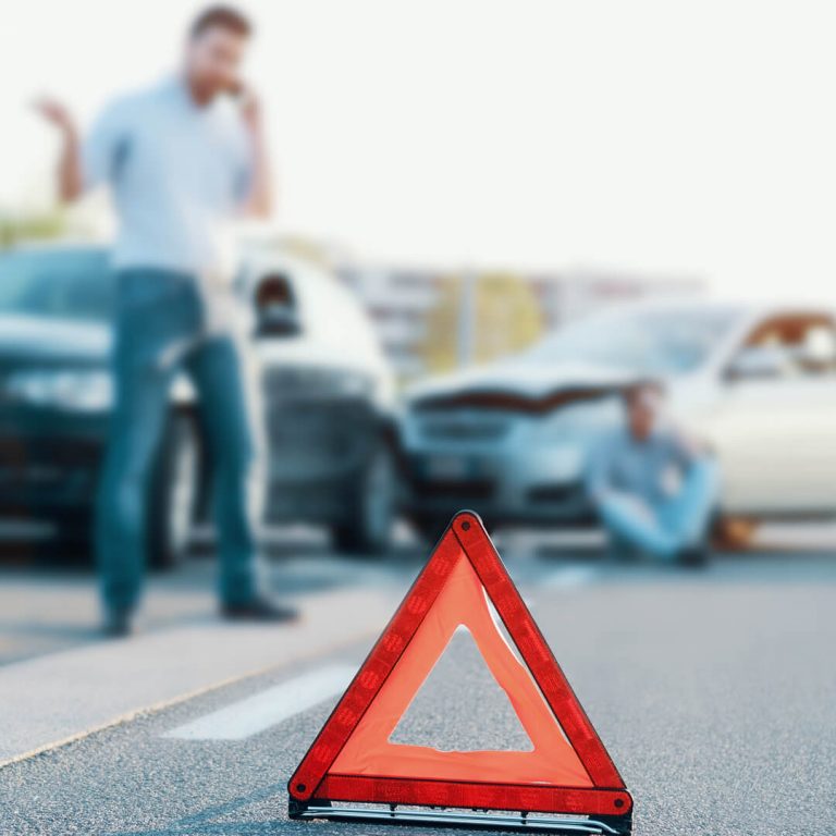 Two people in a car accident, one on the phone calling the police.