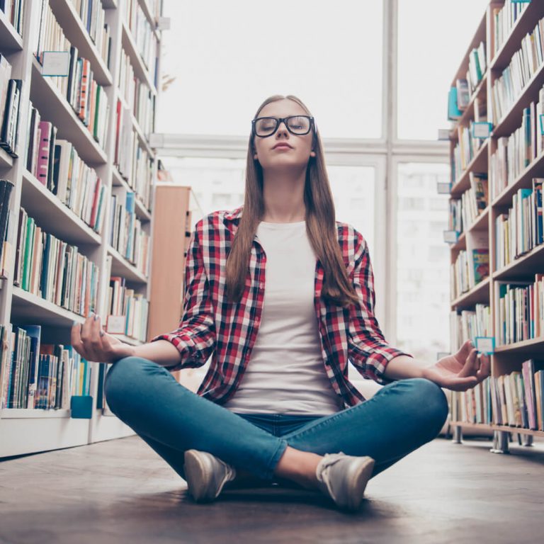 Graduate student practicing yoga in library to de-stress.