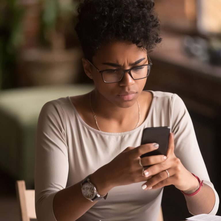Job applicant looks at mobile phone in distress, suspecting job scam.