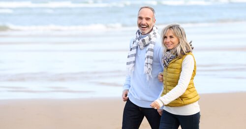 Man and woman smiling and walking down the beach.
