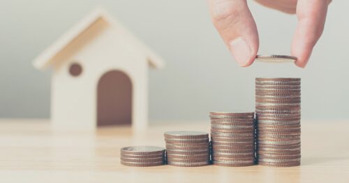 Closeup of table with model home in background, and a stack of change in the foreground.