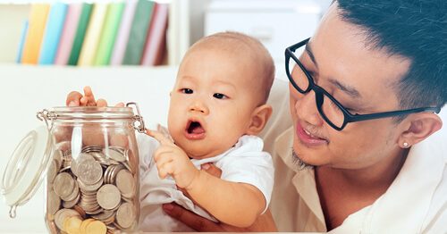 Father and new baby adding change to jar full of coins.