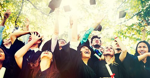 Group of college graduates throwing caps in air.