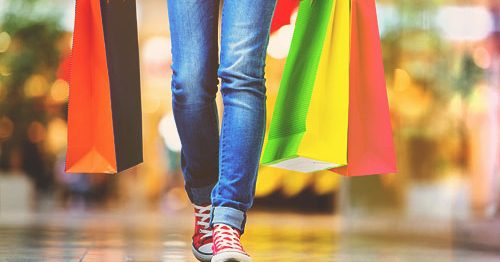 Closeup of teenager's sneakers and shopping bags at mall.